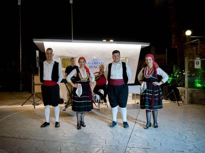 Čtyři lidé v tradičních krojích stojí v noci před bílým pozadím.