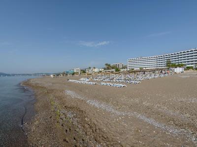 Spiaggia con lettini e ombrelloni accanto a un grande hotel sul mare.