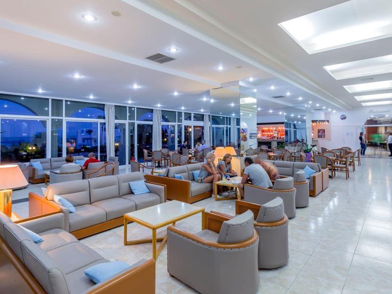 Ampia lounge moderna in hotel con divani, poltrone e tavoli illuminati di notte.