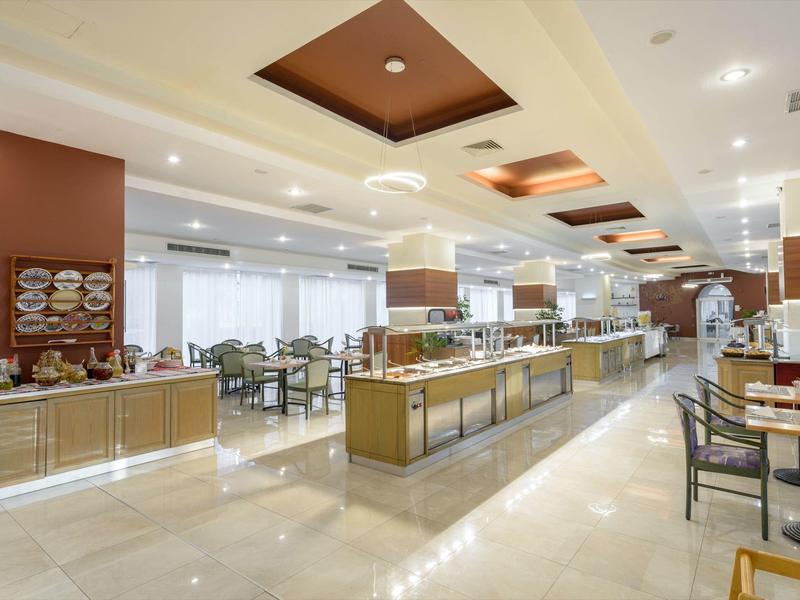 Ristorante d'hotel moderno e luminoso con buffet e area salotto.