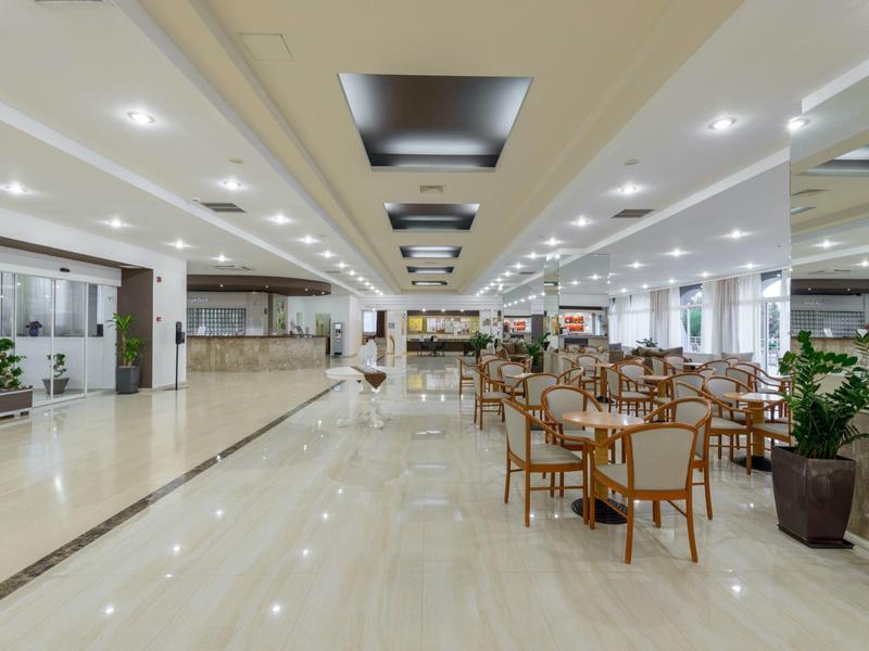 Ampio atrio di hotel luminoso con aree salotto e pavimento in marmo lucido.