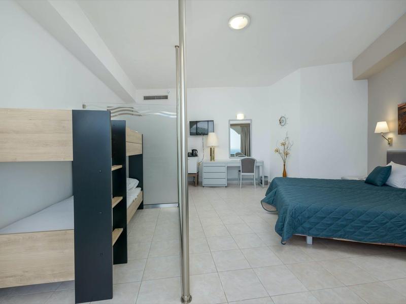 Camera d'hotel luminosa con letto a castello, letto singolo, area salotto e design moderno.