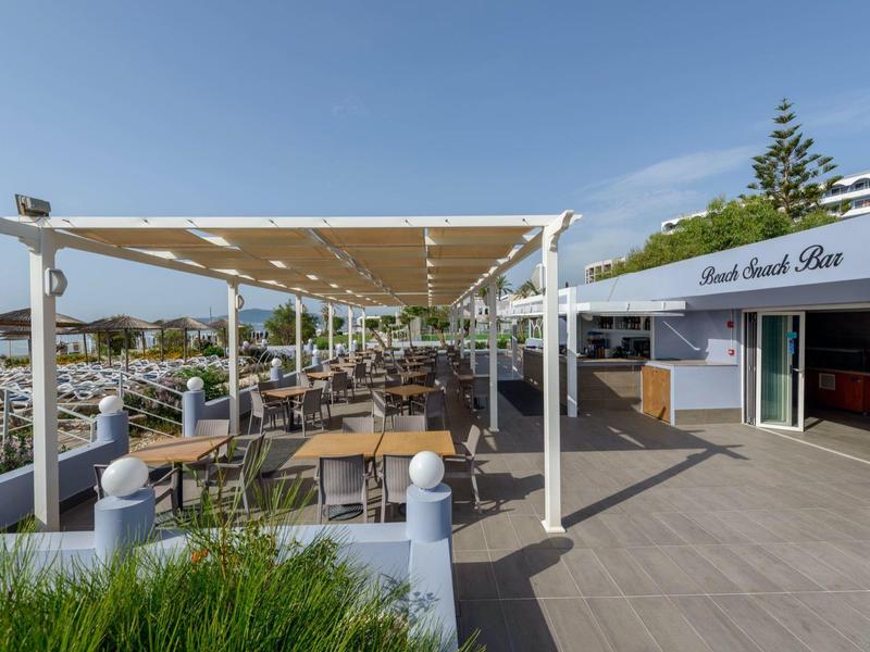 Area esterna con tavoli e sedie accanto a un ristorante dell'hotel sotto cielo sereno.