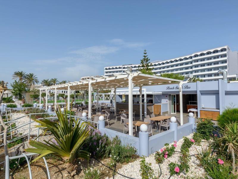 Area esterna dell'hotel con pergola e posti a sedere sotto il cielo sereno.