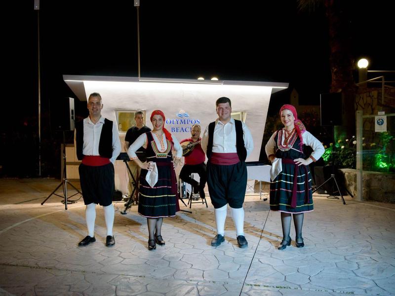 Quattro persone in costumi tradizionali sono davanti a uno schermo in un ambiente buio.