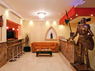 Area lounge elegante dell'hotel con divano in pelle, sgabelli da bar e esposizione di armature