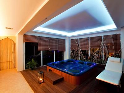 Nowoczesne spa z oświetlonym jacuzzi, leżakiem i dekoracyjnym oświetleniem.