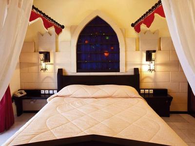 Letto matrimoniale accogliente con tende bianche e lampade da parete in una stanza d'hotel.