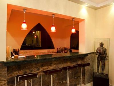 Bar dell'hotel elegante con quattro sgabelli e statua di un cavaliere in un ambiente luminoso e caldo.