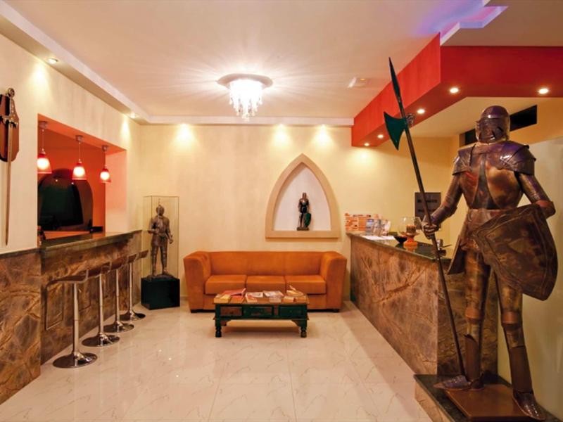 Area lounge elegante dell'hotel con divano in pelle, sgabelli da bar e esposizione di armature