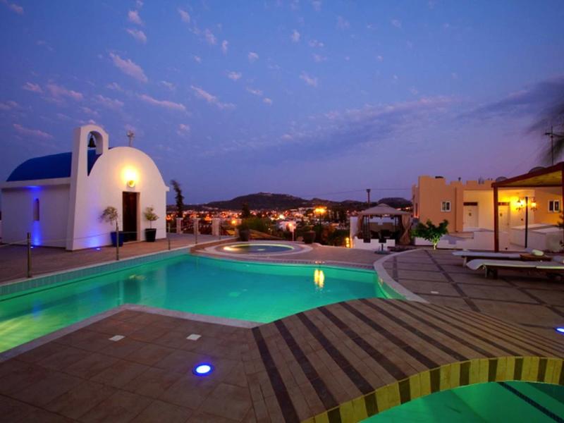 Piscina dell'hotel illuminata con lettini al crepuscolo sotto un cielo azzurro limpido.
