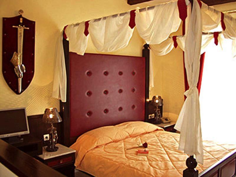 Camera accogliente con letto a baldacchino, tende rosse e bianche e luce calda.