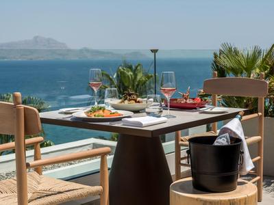 Terras met eettafel en drankjes met uitzicht op de zee en bergen op de achtergrond