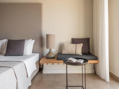 Lichte hotelkamer met bed, bank, tafel en boek voor crème kleurige gordijnen