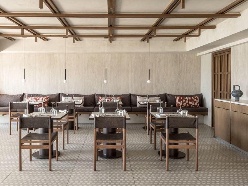 Modern ingerichte eetruimte met houten tafels, stoelen en gedimd licht.