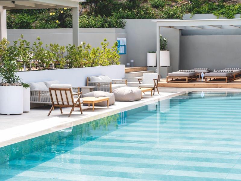 Moderne zwembadomgeving met ligstoelen en loungebanken naast helder water.