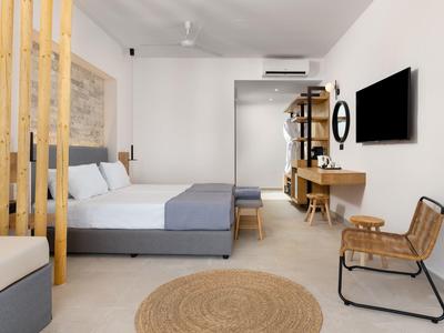 Modernes Hotelzimmer mit Doppelbett, Holzmöbeln, Fernseher und hellem, minimalistischen Design.