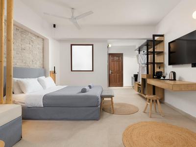 Modernes Schlafzimmer mit grauem Bett, Holzdetails, Wandregalen, runden Teppichen und Fernsehbildschirm.