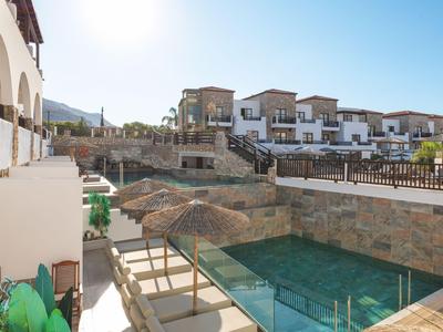 Hotel con piscina al aire libre y terraza soleada bajo un cielo despejado.