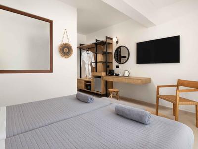 Helles Zimmer mit zwei Betten, grauer Bettwäsche, Holzmöbeln und Wandspiegel.