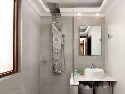Moderner heller Badezimmerbereich mit Dusche, Waschbecken und großem rechteckigem Spiegel.