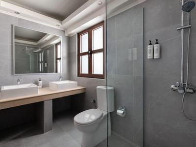 Modernes Badezimmer mit grauen Wänden, Doppelwaschbecken, Toilette und Glasdusche mit Regenduschkopf.