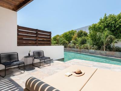Moderner Außenbereich mit Pool, zwei schwarzen Stühlen, Tisch und beigem Liegestuhl bei Sonnenschein.