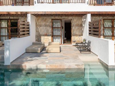 Moderner Terrassenbereich mit Pool, Sonnenliegen und weißen Wänden, Holzelementen und Glasfront.