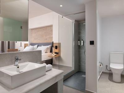 Modernes Badezimmer mit weißem Waschbecken, Spiegel, Dusche und WC in schlichtem Design.