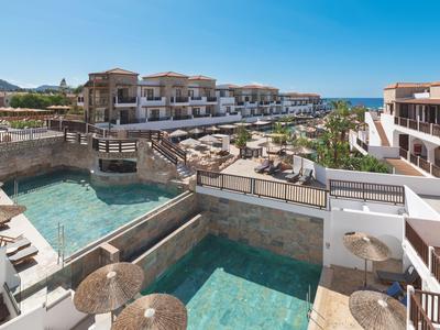 Resort de lujo con varias piscinas, terraza y vista al mar bajo cielo despejado.