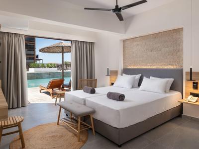 Modernes Schlafzimmer mit großem Bett, Hocker, Ventilator und Zugang zu Terrasse mit Pool und Liegestühlen.