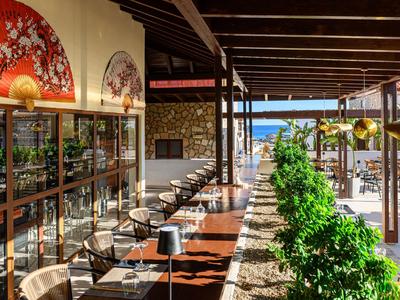 Espace d'hôtel ouvert avec assises et vue sur la mer en arrière-plan.
