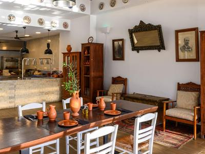 Salle à manger d'hôtel lumineuse avec tables en bois, vaisselle en céramique et décorations traditionnelles.