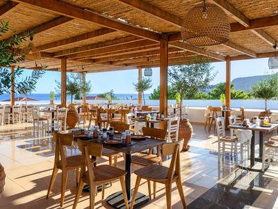 Offener, sonniger Essbereich mit Holzmöbeln in einem Hotel nahe Wasser und Bergen.