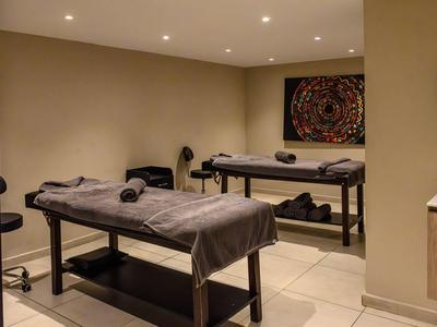 Elegante sala massaggi con due lettini e decorazione murale rilassante.