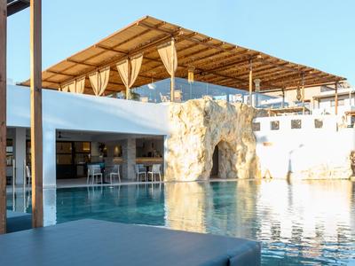 Piscina moderna de hotel con cascada y toldo bajo un cielo despejado