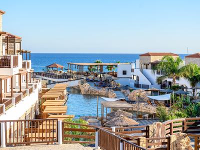 Resort vacacional con vistas al mar, piscina y varios edificios bajo cielo despejado.