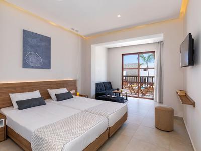 Chambre d'hôtel moderne avec deux lits simples, balcon vue mer et décoration minimaliste.