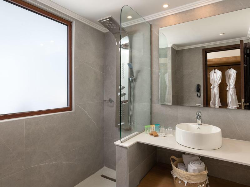 Bagno moderno con doccia a pioggia, lavabo su piano e finestra satinata.