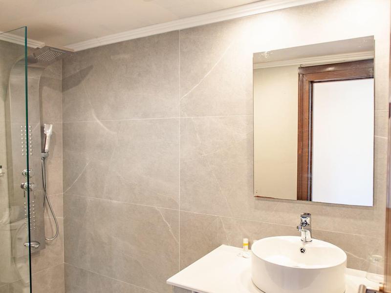 Bagno moderno con doccia a filo pavimento, lavabo in appoggio e asciugamani sotto.