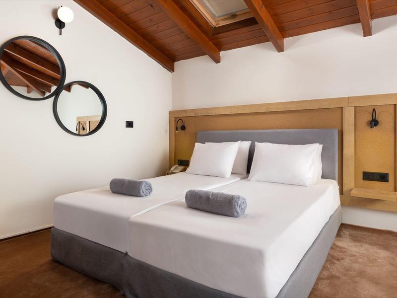 Camera moderna con letto matrimoniale, biancheria bianca e eleganti specchi rotondi sulla parete.