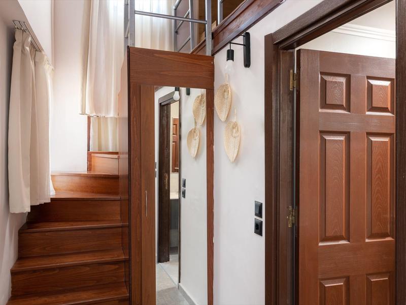 Scala in legno accanto a uno specchio e una porta di legno aperta in un corridoio d'hotel