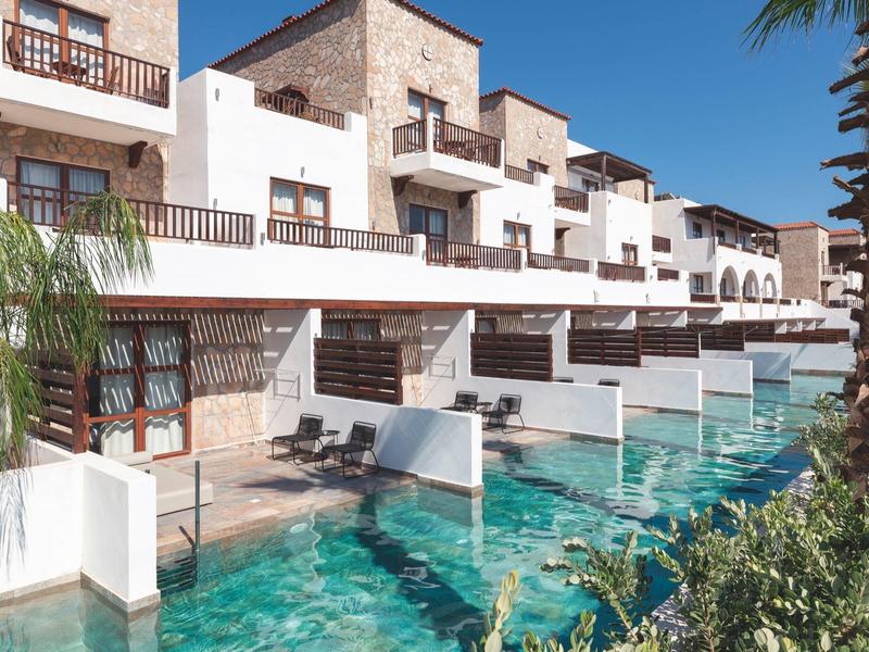Hotel con piscine private davanti alle camere e balconi sotto un cielo azzurro terso.