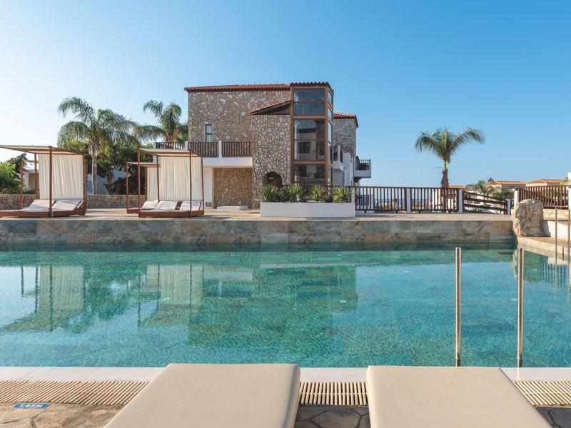 Piscina moderna dell'hotel con vista su un edificio su più piani e palme.