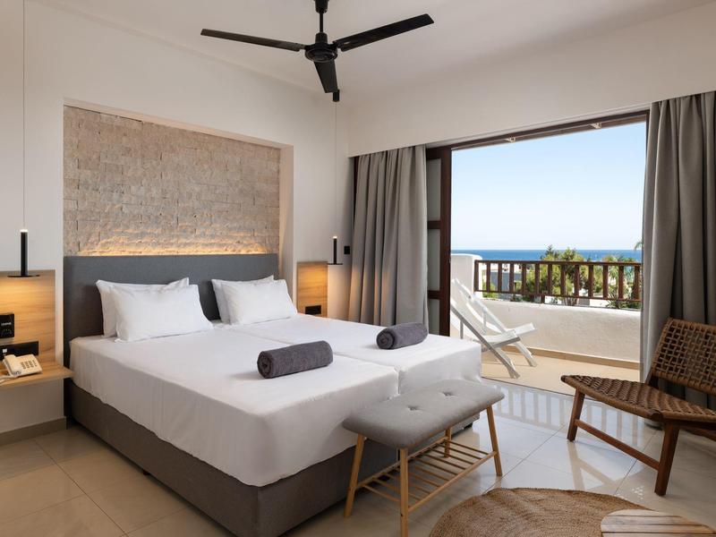 Camera d'hotel moderna con letto matrimoniale, balcone e vista mare.