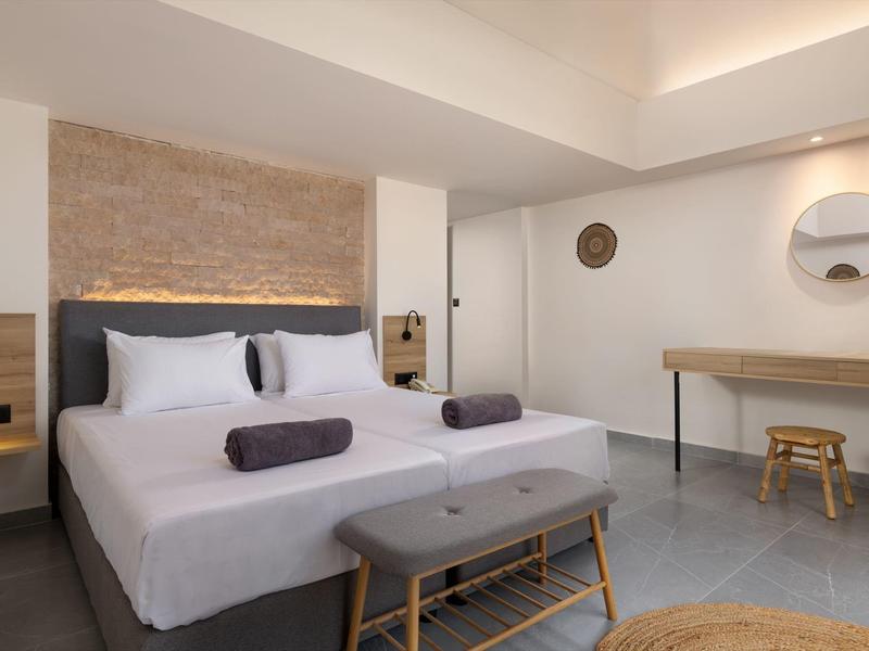 Camera d'hotel moderna con letto matrimoniale, pareti chiare e arredi minimalisti.