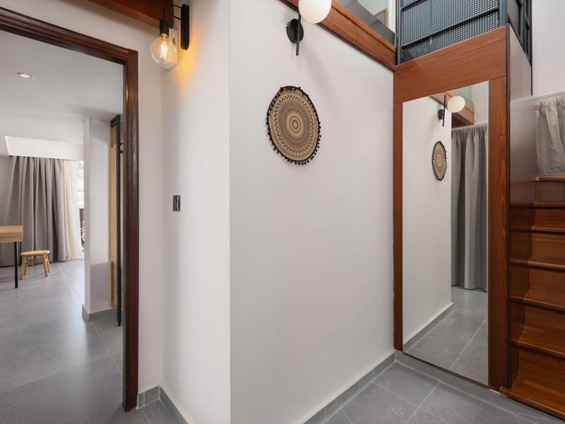 Corridoio stretto moderno con specchio, scale in legno e luce naturale in una camera d'hotel.