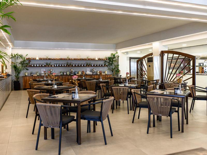 Ristorante moderno dell'hotel con tavoli e sedie in legno e un bar sullo sfondo.