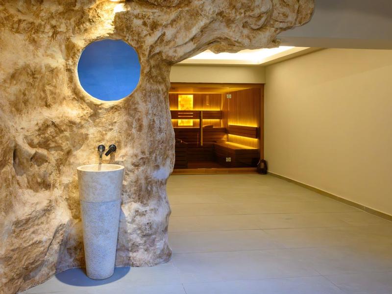 Interno moderno con parete rocciosa, lavandino e zona salotto accogliente sullo sfondo.