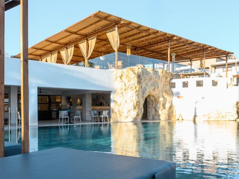 Piscina moderna dell'hotel con elemento roccioso e area coperta sotto cielo sereno